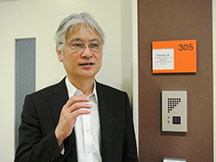 施設内の「東京営業所」の前で、「この技術で世界に貢献したい」と語る松浦社長